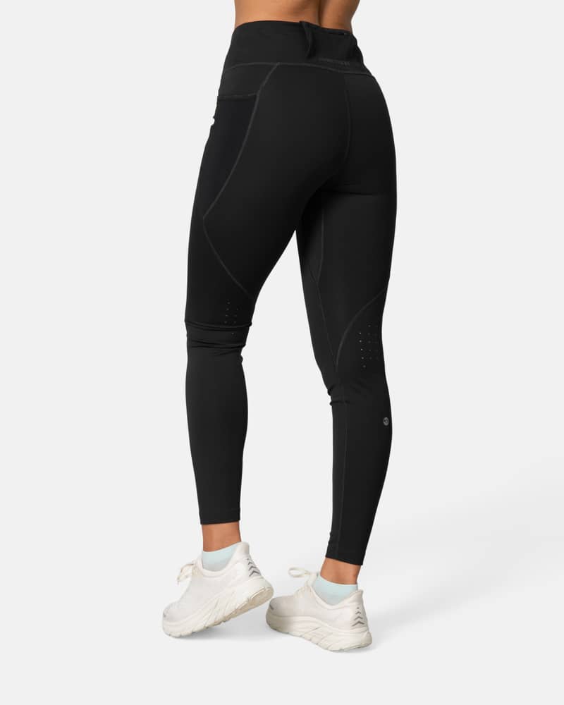 Back-side view of a woman in the black Kari Traa Nia Tights, highlighting the flattering fit and secure back pocket.