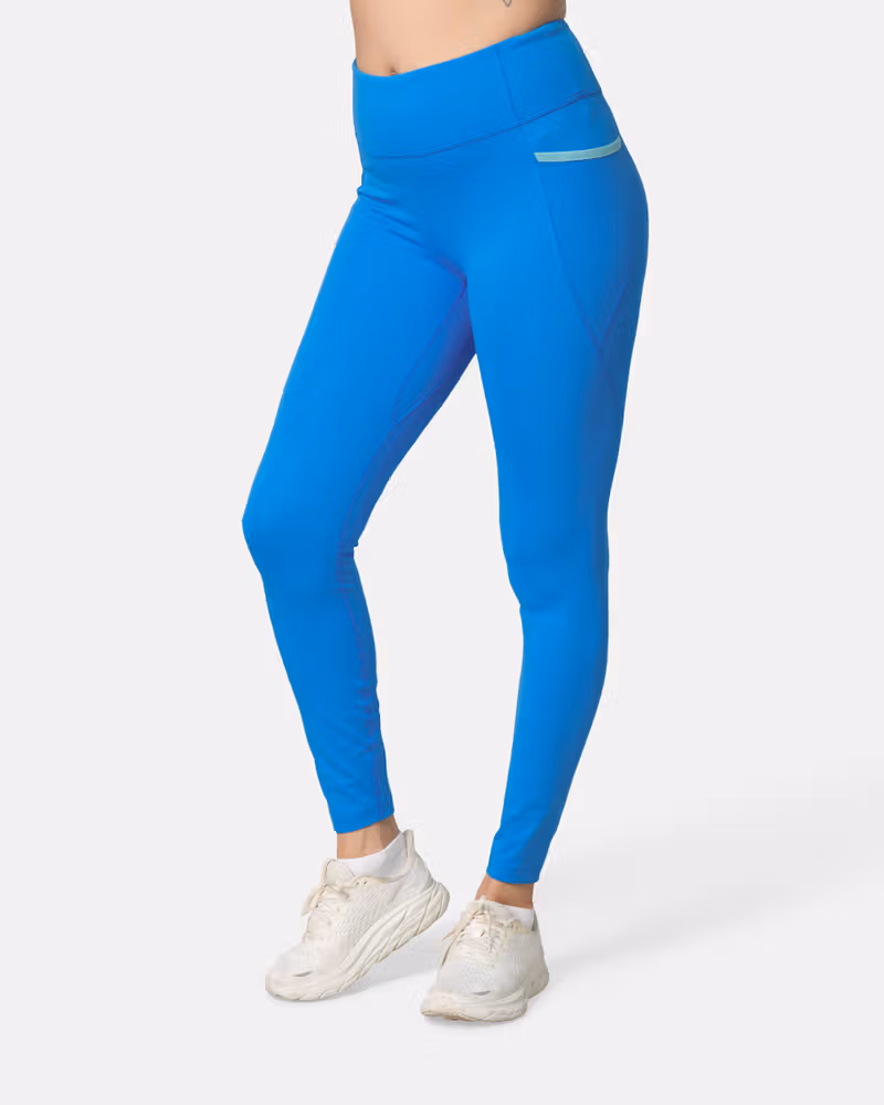 Woman wearing the horizon blue Kari Traa Nia Tights, showing their slim fit and side pocket for training.