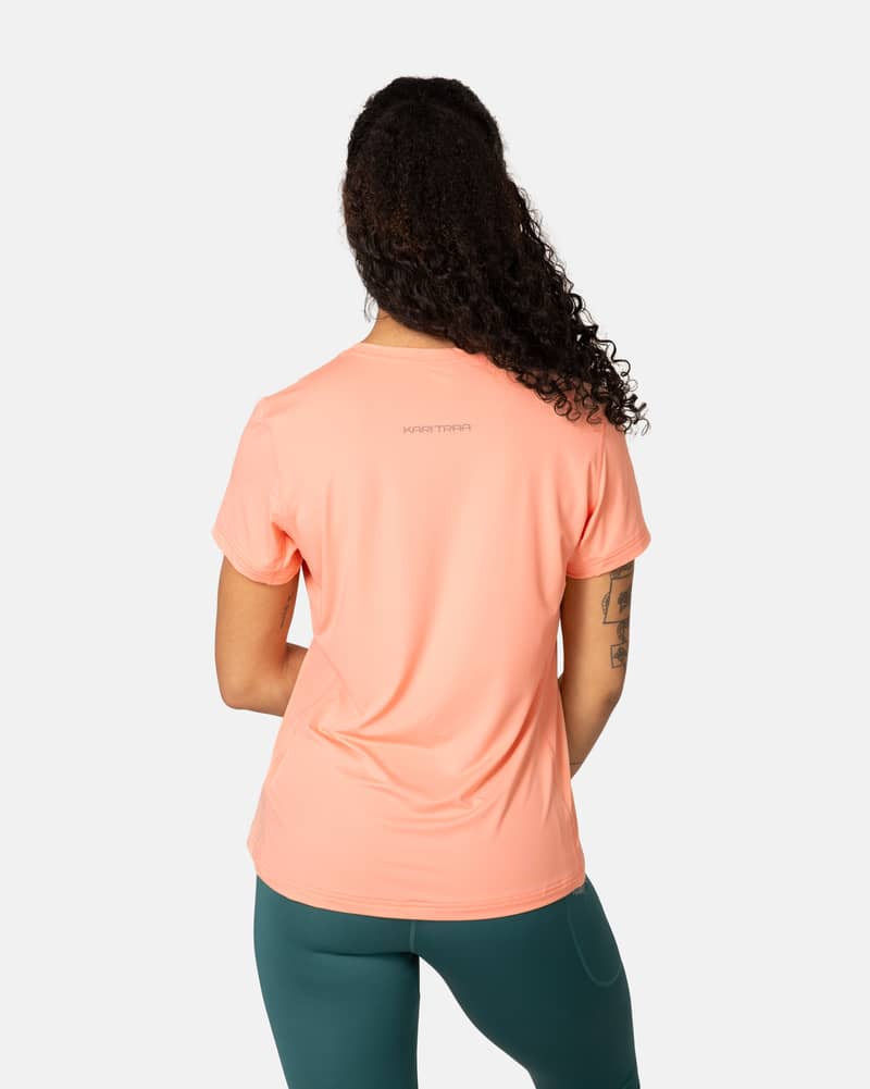 Back view of the peach Kari Traa Ava Tee, showing its curved hem and smooth flatlock seams for comfort.