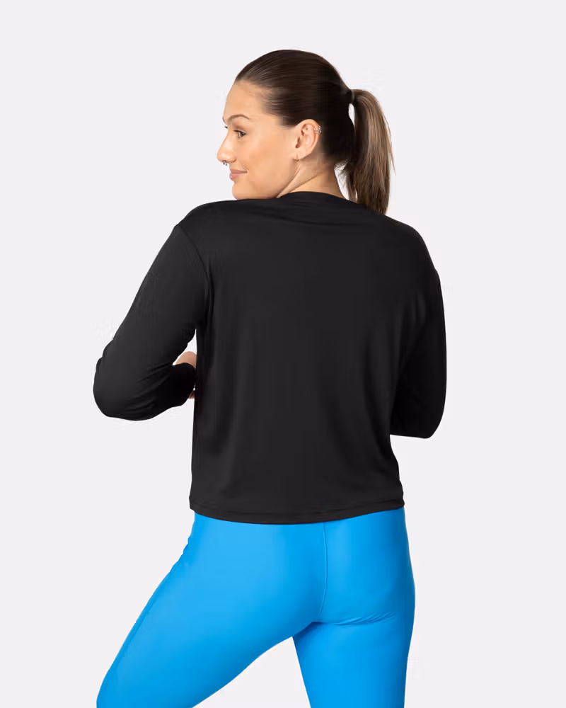 Back view of a woman in the black Kari Traa Una Long Sleeve, showing its relaxed fit for active and casual wear.