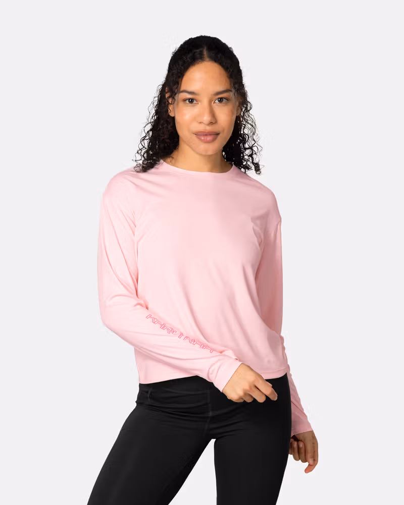 Woman wearing the Kari Traa Una Long Sleeve in pastel pink, a quick-drying top with UPF 40+ sun protection.