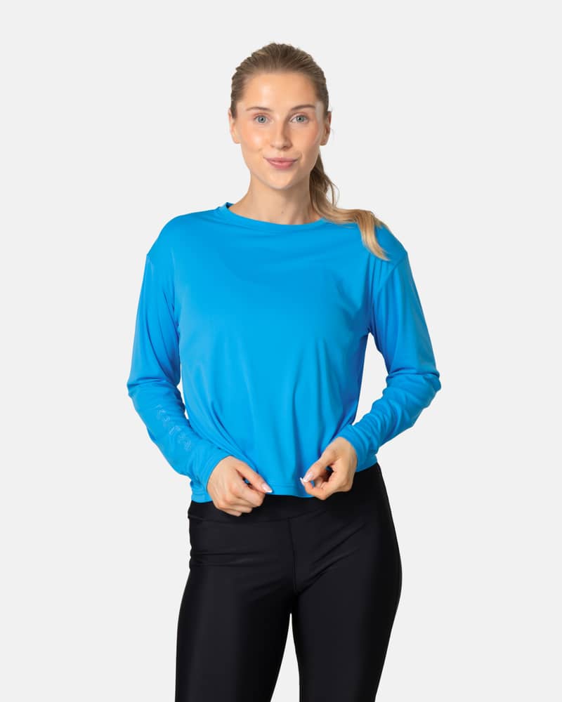 Woman wearing the Kari Traa Una Long Sleeve in blue horizon, a quick-drying top with UPF 40+ sun protection.