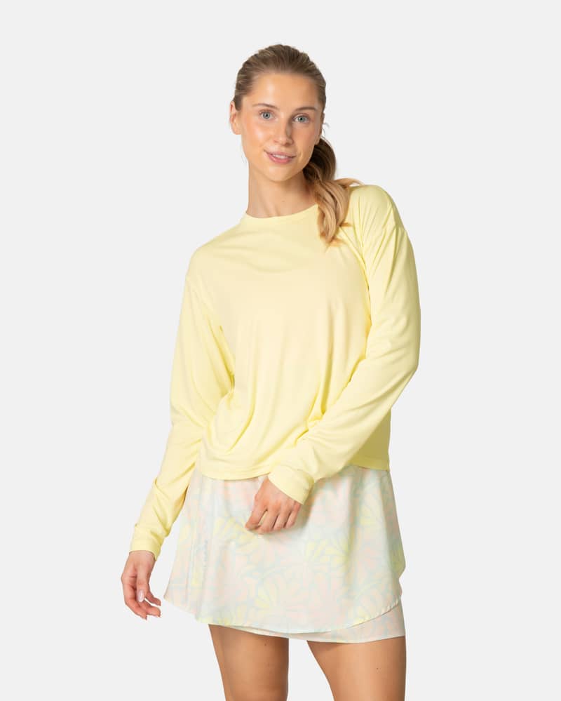 Woman wearing the Kari Traa Una Long Sleeve in light yellow, a quick-drying top with UPF 40+ sun protection.