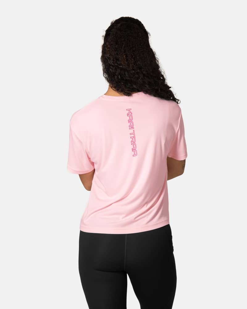 Back view of a woman in the pastel pink Kari Traa Una Tee, showing the vertical logo detail down the spine.
