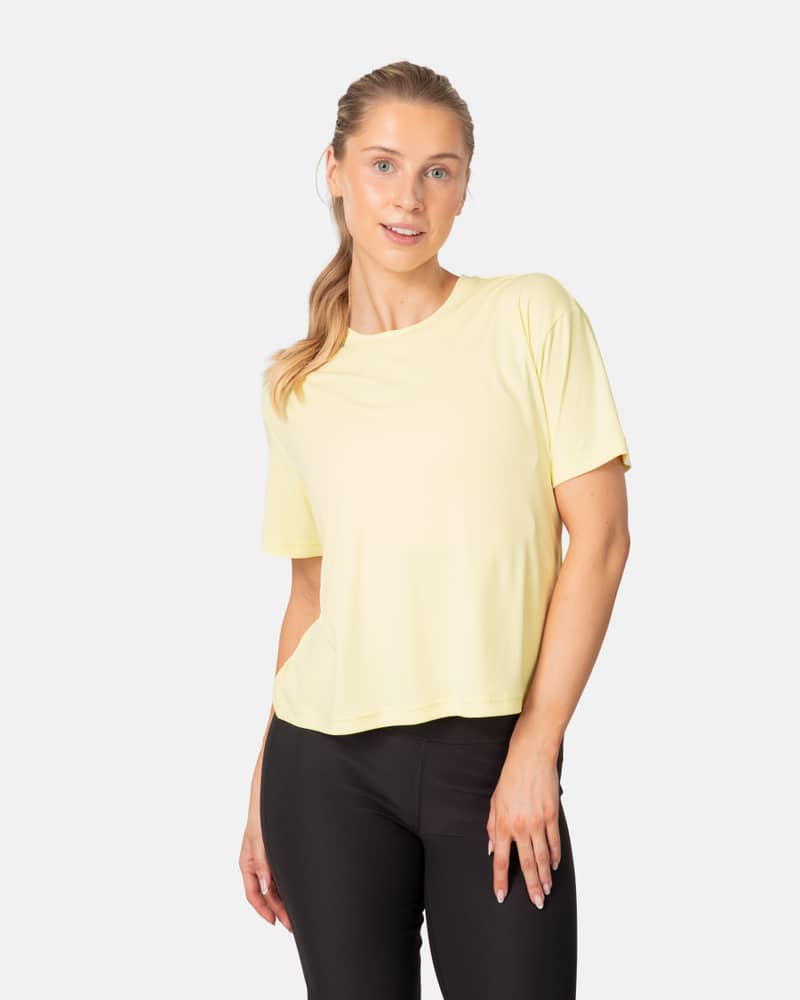 Woman wearing the Kari Traa Una Tee in yellow, a relaxed-fit shirt for workouts and warm weather adventures.