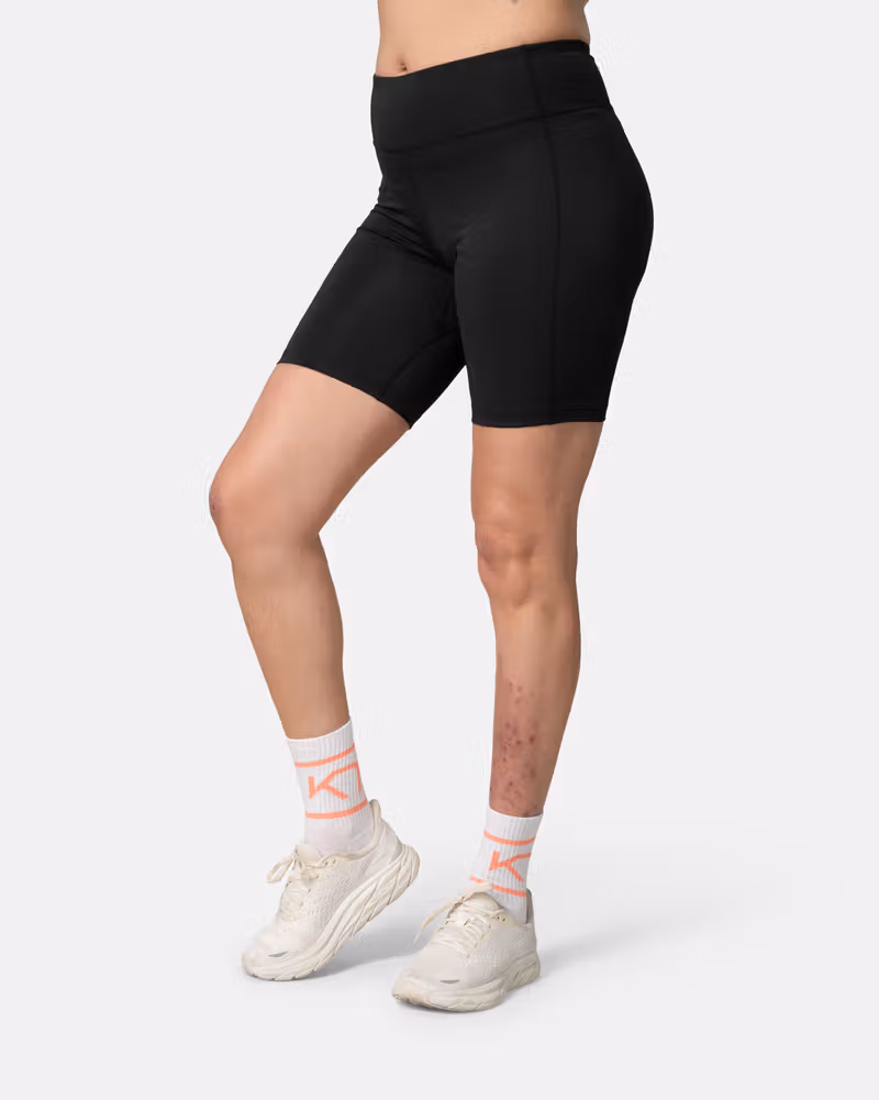 Side view of a woman wearing the black Kari Traa Ava 8-inch Shorts, showing the 8-inch inseam and slim fit.