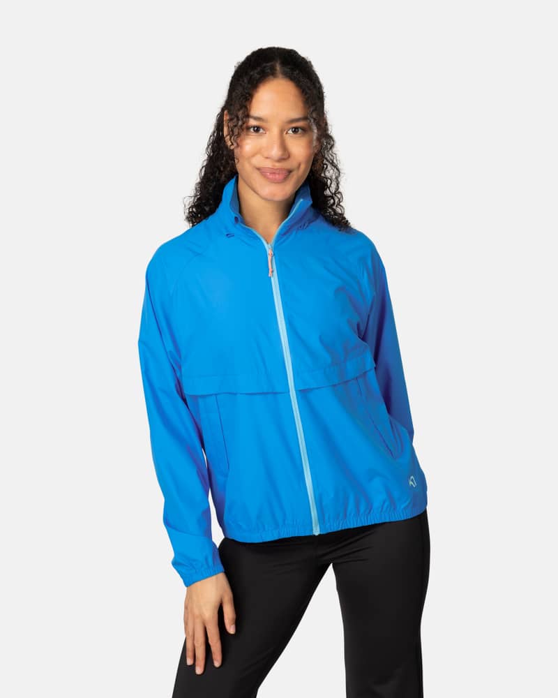 Woman wearing the bright blue Kari Traa Nia Wind Jacket with a full-zip front, perfect for running or hiking.