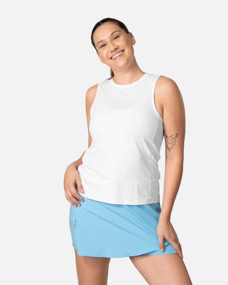 Woman wearing the white Kari Traa Ava Tanktop, a versatile training top styled for a gym workout.