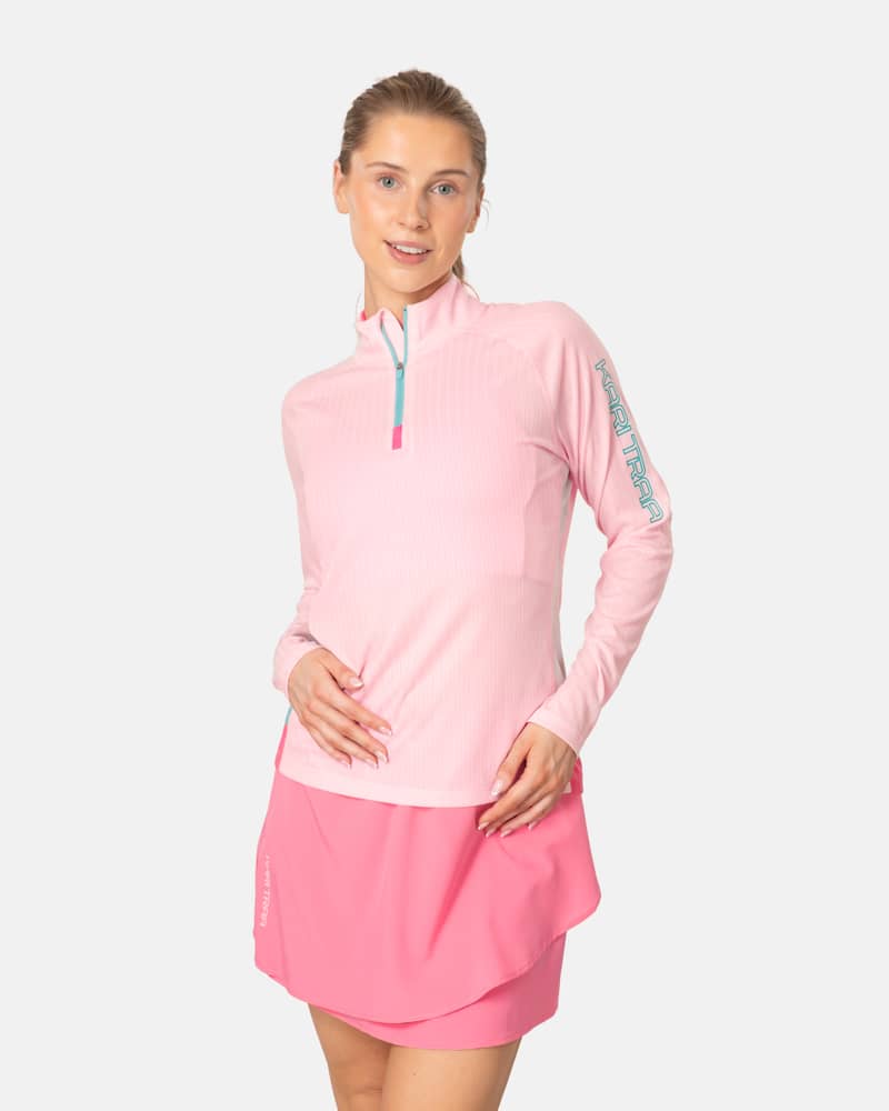 Woman wearing the pink Kari Traa Leah Half Zip base layer with blue contrast details on the sleeves and zipper.